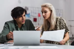 Two people talking in front of a computer