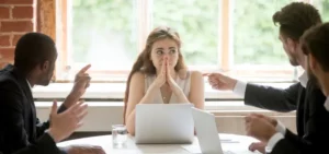 girl in a meeting with bosses pointing at her